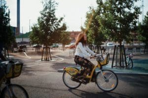 Two girls are riding through Kalasatama using Helsinki city bikes on a sunny day