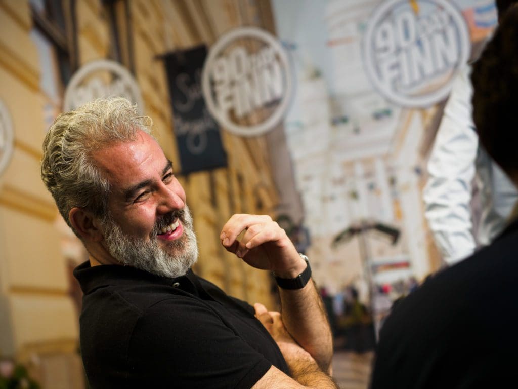 Andro Lindsay, part of the 90 Day Finn 2021 programme and Co-founder of 100 Thousand Million, smiles and laughs with someone sitting to their right.