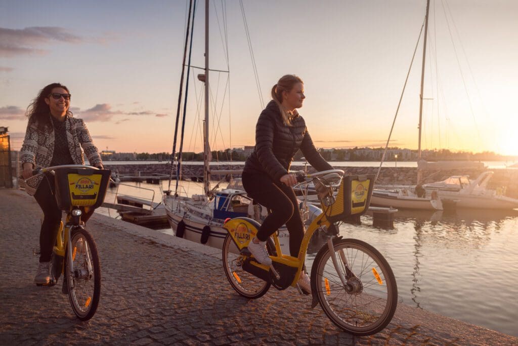 Two women on a pier riding Helsinki city bikes