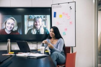 Woman in a virtual meeting with two smiling faces on the screen behind her