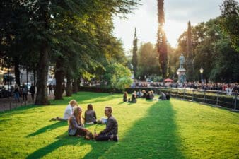As sunny and green Esplanade Park during Helsinki Festival, with people sitting on the grass.