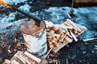 Axe in a wood stump surrounded by logs