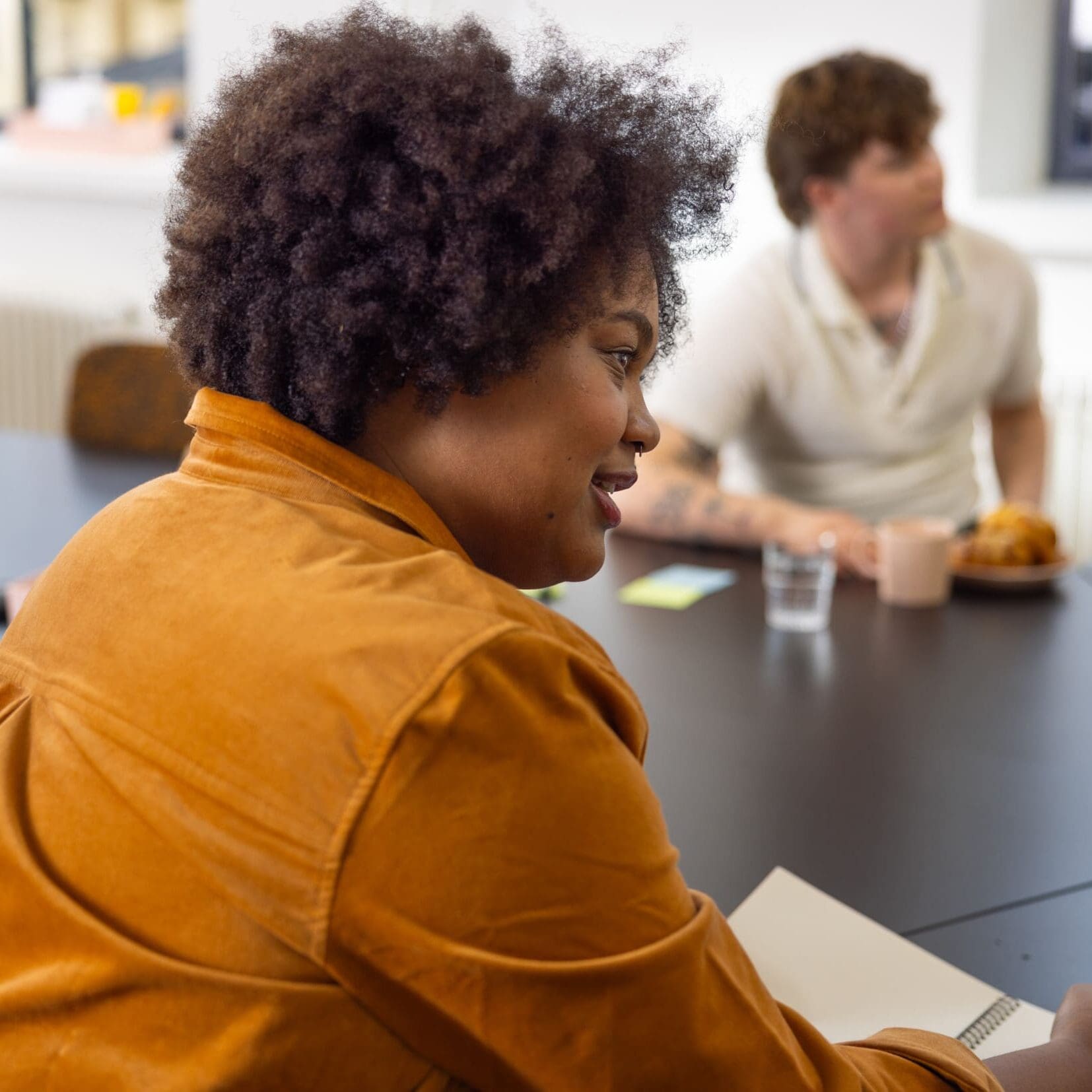 A woman sits at a table writing and talking